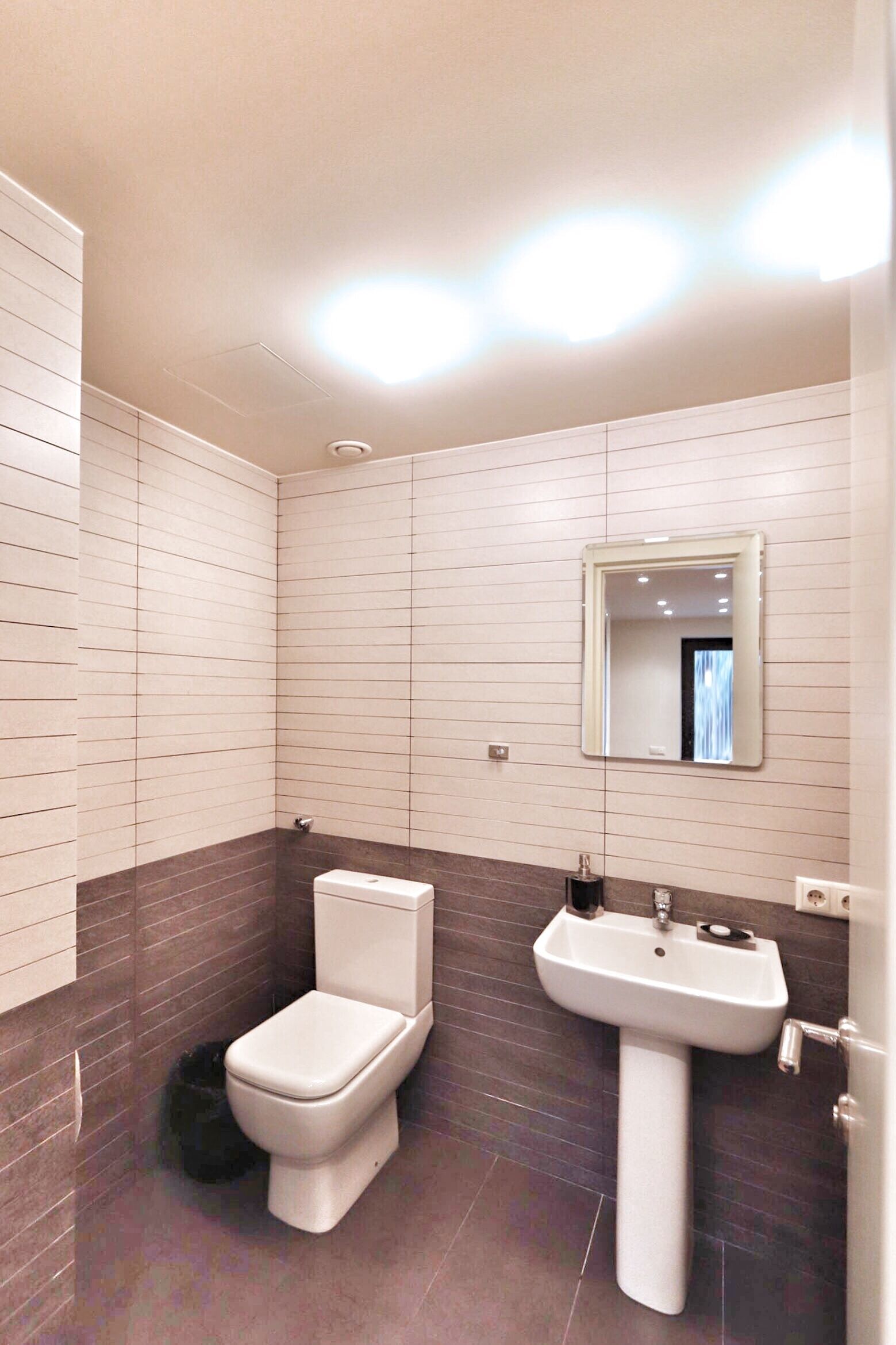 A modern bathroom with a toilet, sink, and mirror.