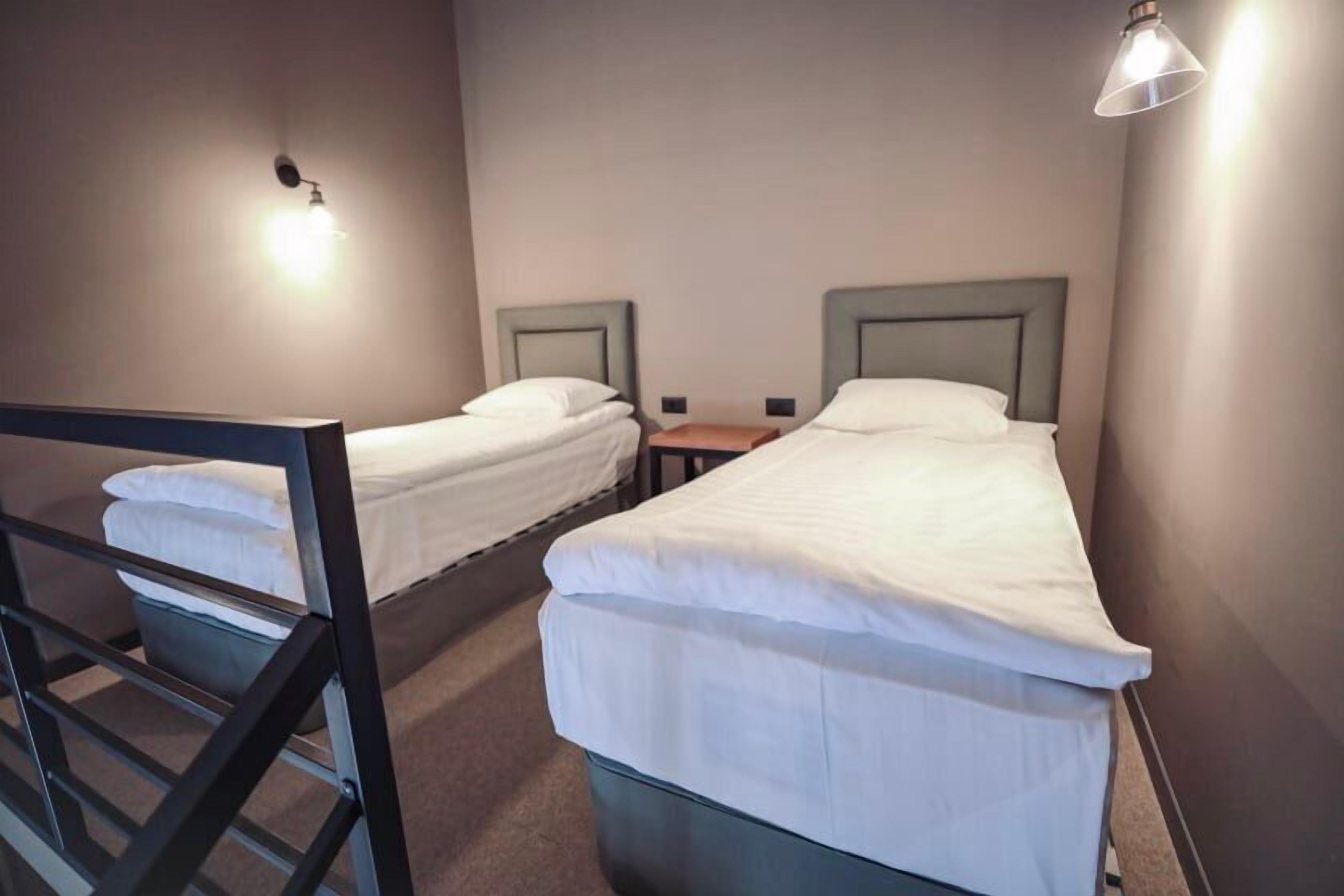 Une chambre avec deux lits simples, chacun doté d’une tête de lit et d’une table de chevet.