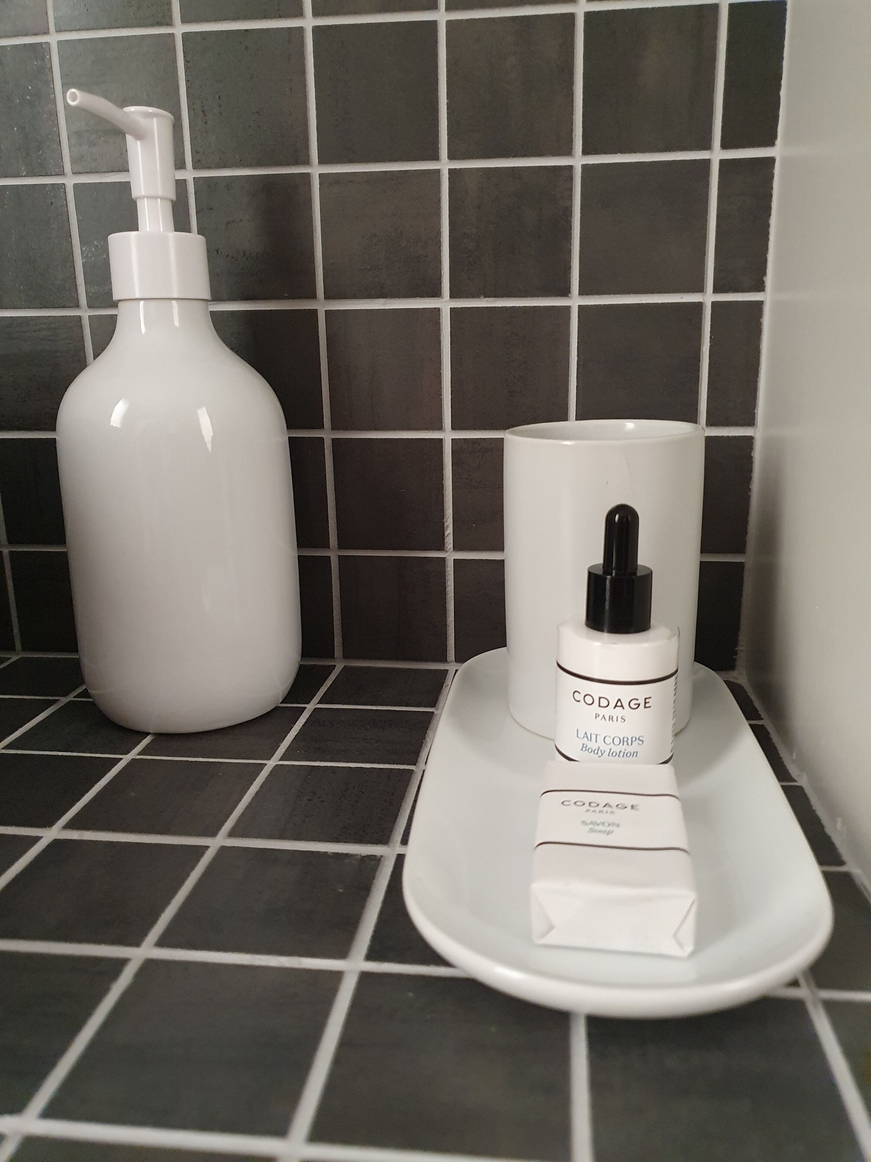 Un bagno con un lavandino bianco, una bottiglia di lozione bianca e un flacone dispensatore bianco.
