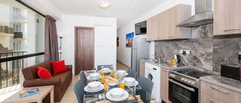 Un appartement moderne comprenant un coin repas, un canapé, une cuisine équipée d’une cuisinière et un lave-linge.