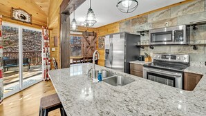 A modern kitchen with granite countertops, stainless steel appliances, and wooden accents. - Enchanted Memories- Less than a mile to Pigeon Forge!  Home Theater! (Pigeon Forge)