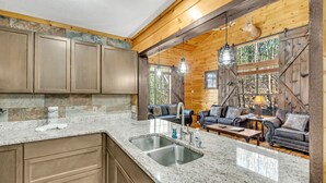 Eine Küche mit Granit Arbeitsplatten, einer doppelten Spüle und Holzschränken. Es gibt eine Sitzecke mit Ledersofas und einem aufgehängten Hirschkopf.