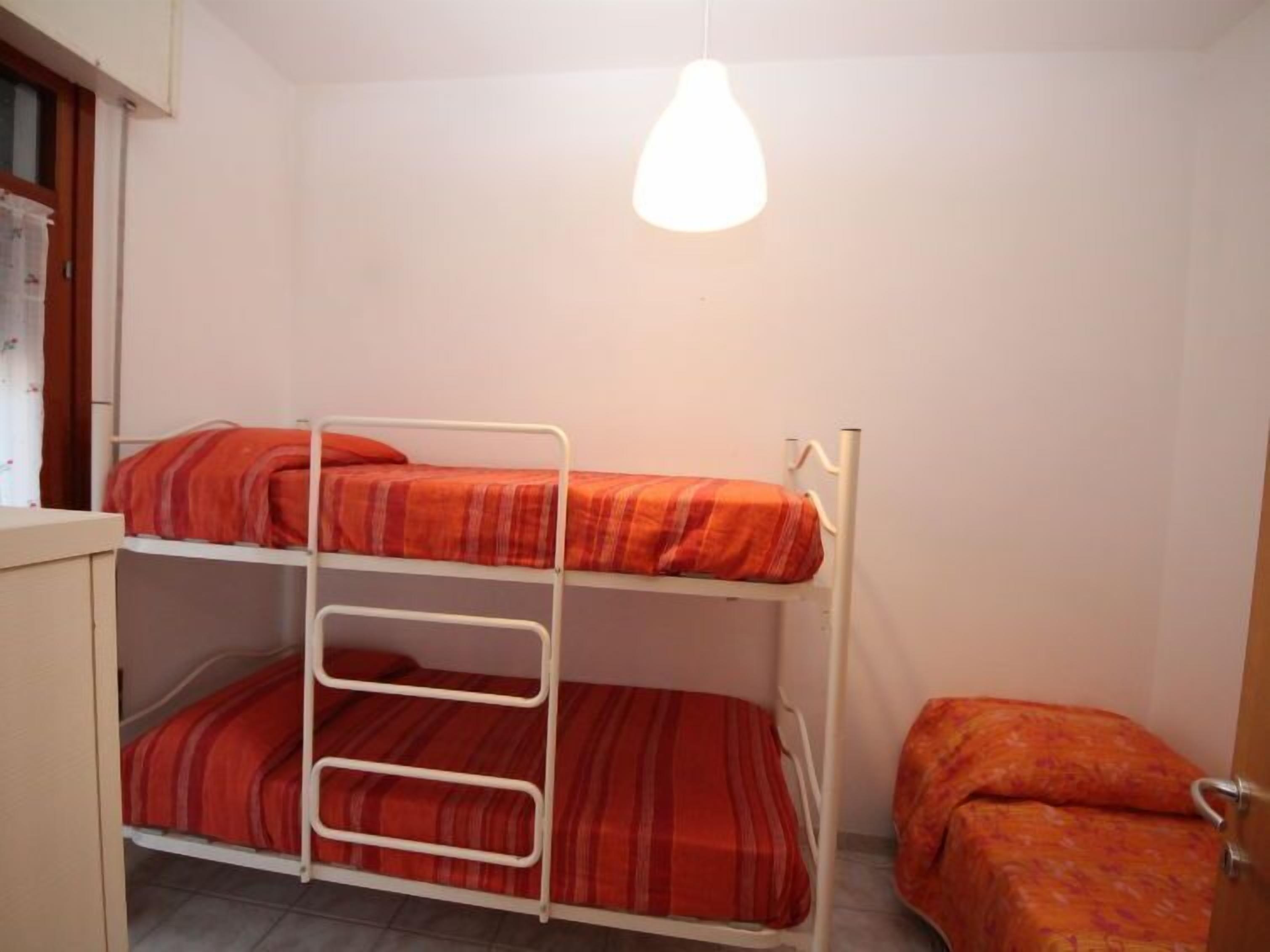 Ein Schlafraum mit Etagenbett, einer einzelnen Bettliege und einer Hängeleuchte.