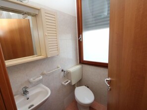 A small bathroom with a sink, toilet, and a mirror above the sink.