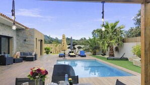 Un espace aménagé au bord de la piscine, avec une table dressée pour les repas, des chaises longues et une vue sur la piscine.