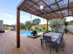 Un patio techado al aire libre con piscina, mesa de comedor y sillas de descanso.