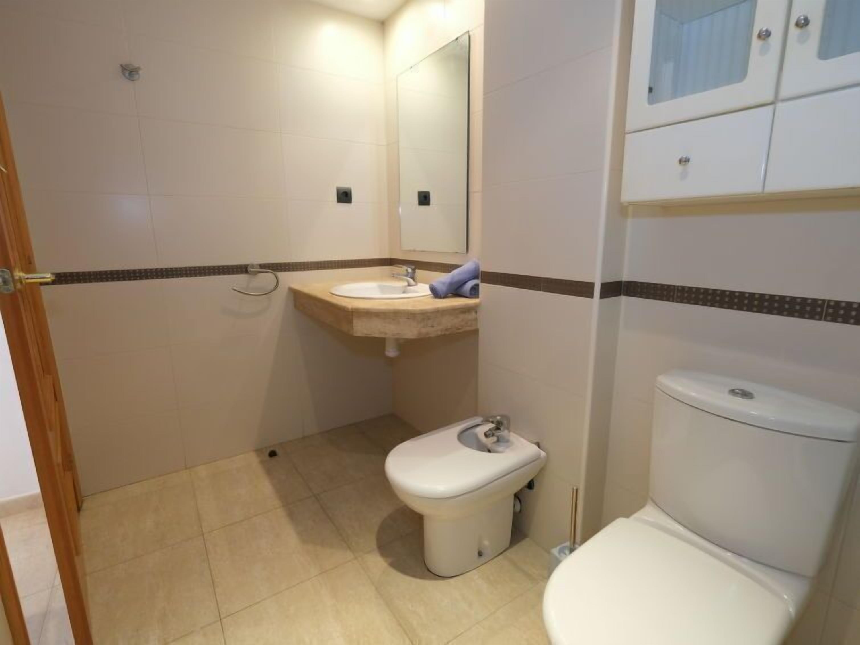 Une petite salle de bain compacte, équipée de toilettes, d’un lavabo et d’un miroir.