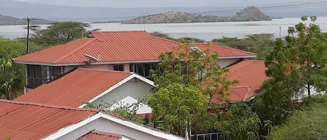 Un barrio residencial con casas de techos rojos y paredes blancas, rodeado de vegetación y una masa de agua al fondo.
