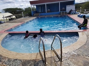 Una piscina con zona techada y un cartel que indica las normas y reglamentos.