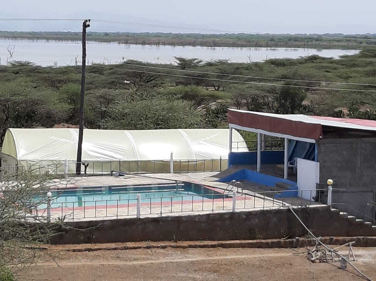 Una piscina con area coperta, un piccolo edificio e vista su un lago.