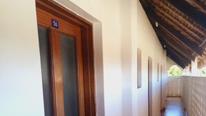 Un couloir avec une porte en bois portant le numéro « 56 », des murs blancs et un sol carrelé.