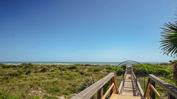 Una pasarela de madera que conduce a una playa con vista despejada al océano.