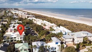 Vista aérea de una zona residencial costera con acceso a la playa, que muestra una combinación de casas unifamiliares y un gran hotel con piscina.