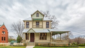 A two-story house with a porch, a covered front porch area, and a small garden. - Luxurious King Room in Historic Boutique Inn (Winston-Salem)