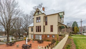 A two-story building with a brick facade and a large patio area with outdoor seating. - Luxurious King Room in Historic Boutique Inn (Winston-Salem)