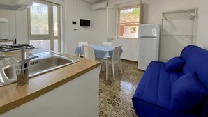 A compact kitchen with a sink, stove, and a dining area with a table and chairs. - Villetta Pasquina - Bilo 4 (Puglia)