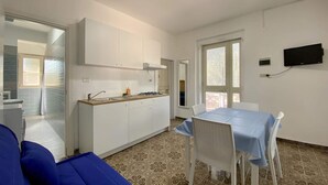 A compact living space with a kitchenette, a dining area, and a sofa. - Villetta Pasquina - Bilo 4 (Puglia)