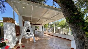 An outdoor patio area with a covered seating area, a brick wall, and a tree. - Villetta Pasquina - Bilo 4 (Puglia)
