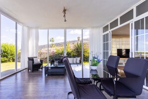 A spacious room with large windows, a sofa, chairs, and a small table. - Fantastic home with amazing sea views (El Sauzal)