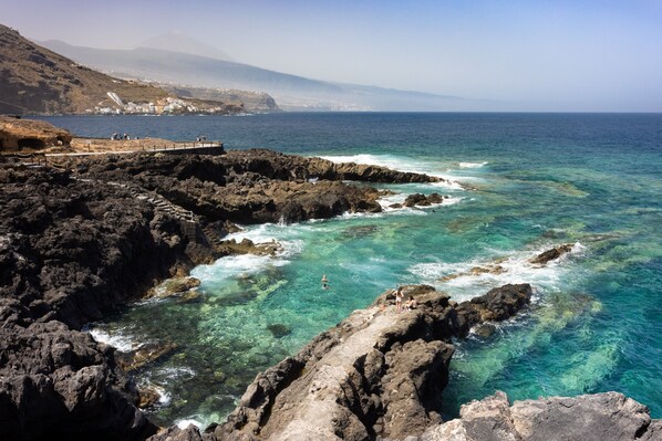 A coastal landscape with rocky terrain and clear blue waters.