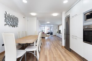 A modern kitchen with a dining area, stainless steel appliances, and a view to the outside.