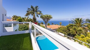 Un bâtiment moderne doté d’une piscine, d’une végétation luxuriante et offrant une vue sur l’océan.