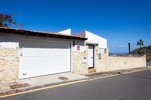 Un edificio con puerta de garaje blanca, paredes de piedra y un cielo azul despejado.