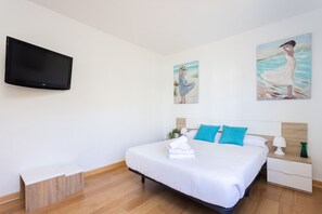 A hotel room with a bed, a TV, and artwork on the walls.