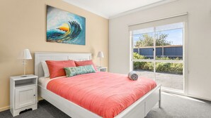 Ein Schlafzimmer mit einem großen Bett, zwei Nachttischen, einem Gemälde und Blick ins Freie.