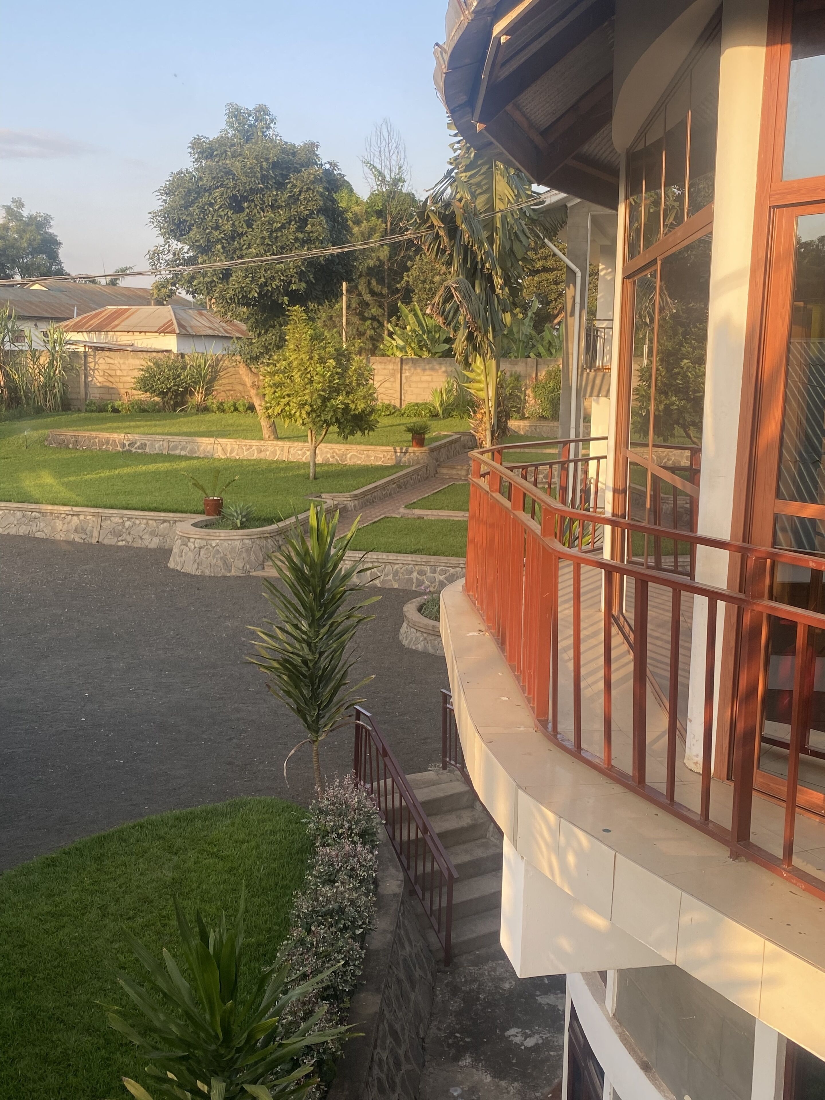 A residential building with a balcony, a stone pathway, and a lawn.