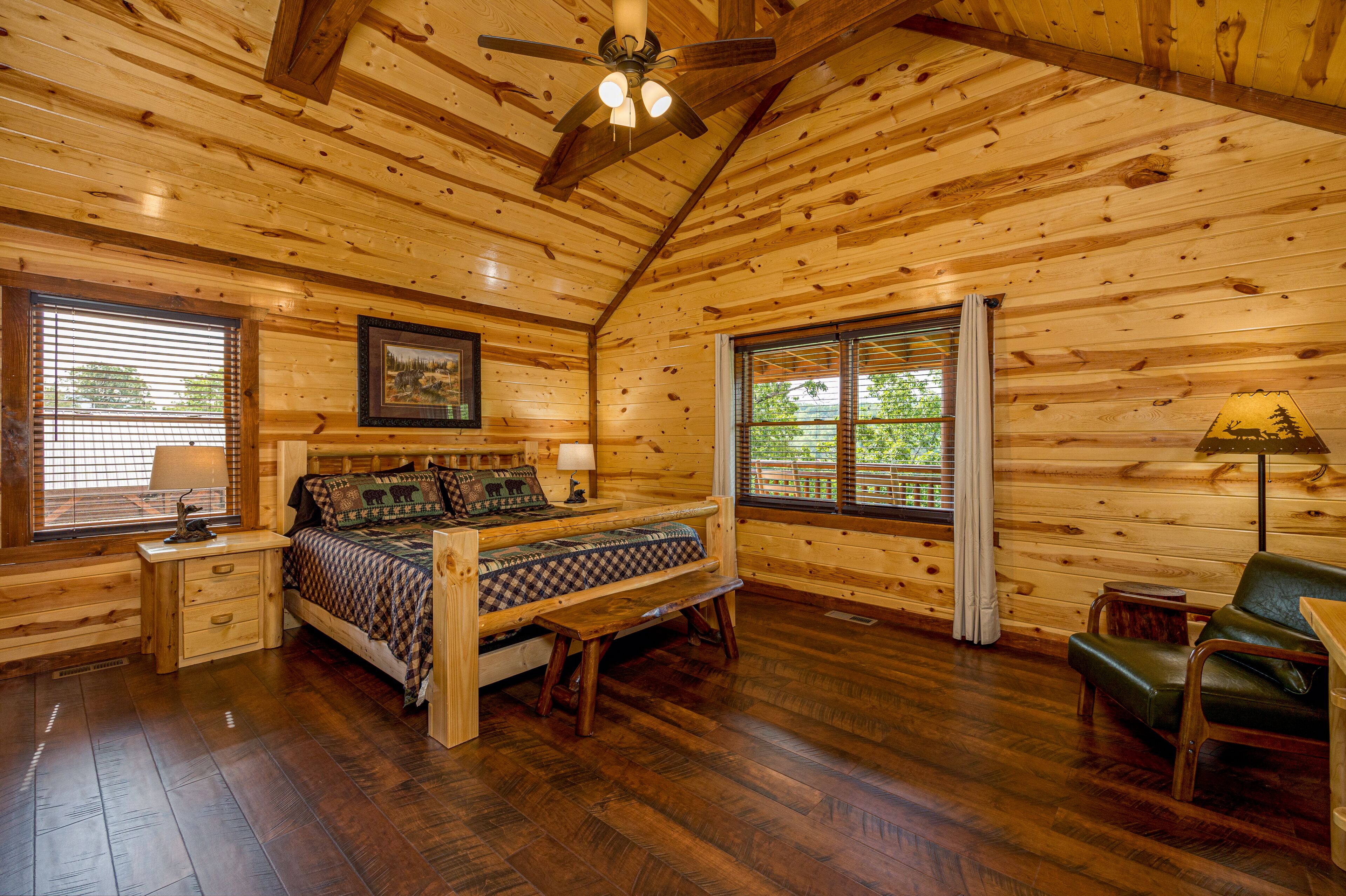 Interior de una cabaña de madera con una cama, un banco, un escritorio y una silla.