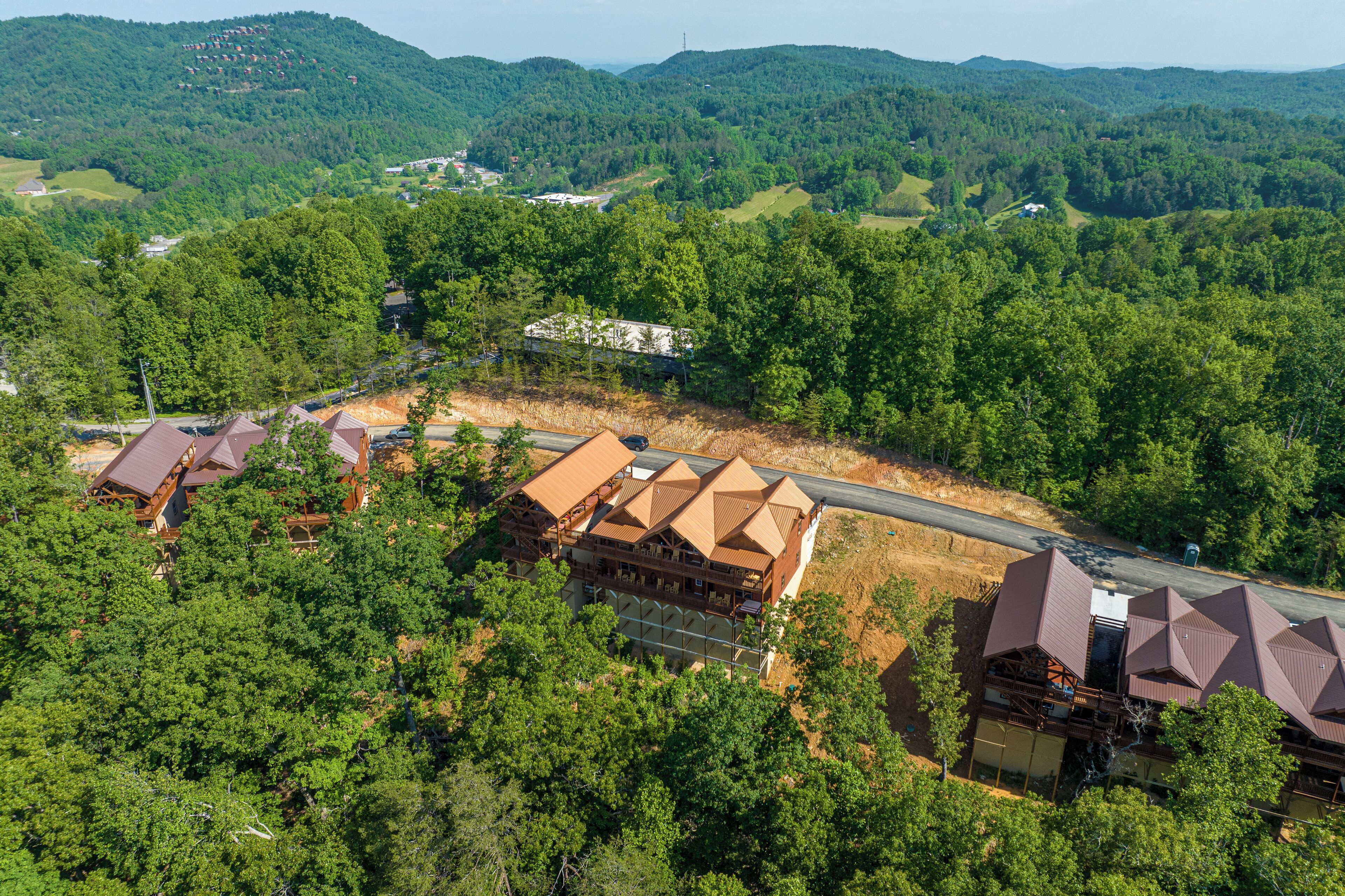 A lodge with multiple cabins, surrounded by dense forest and hills.
