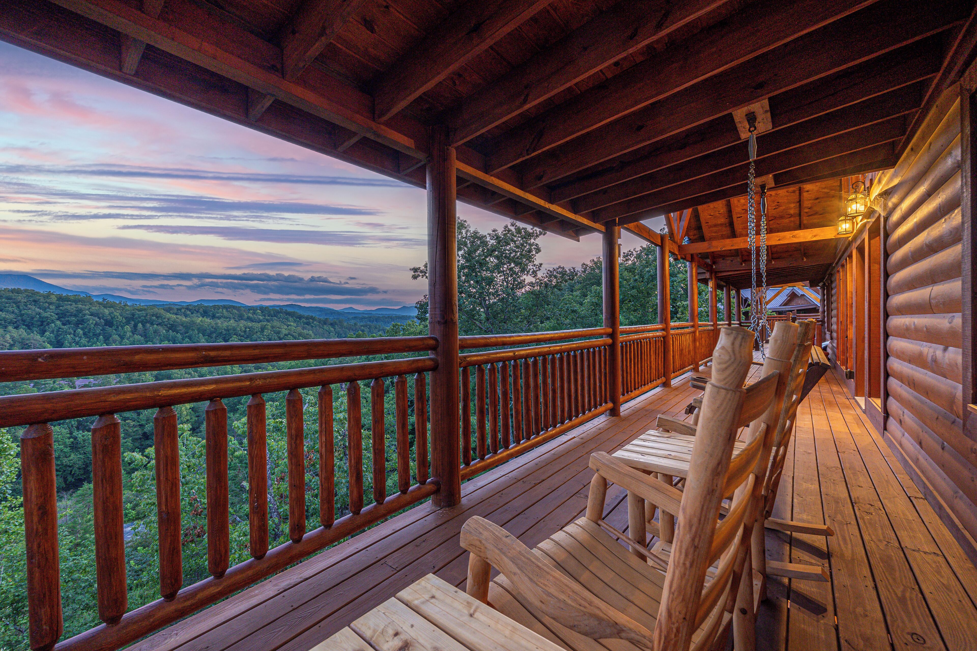 A wooden deck with a railing overlooking a forested landscape.