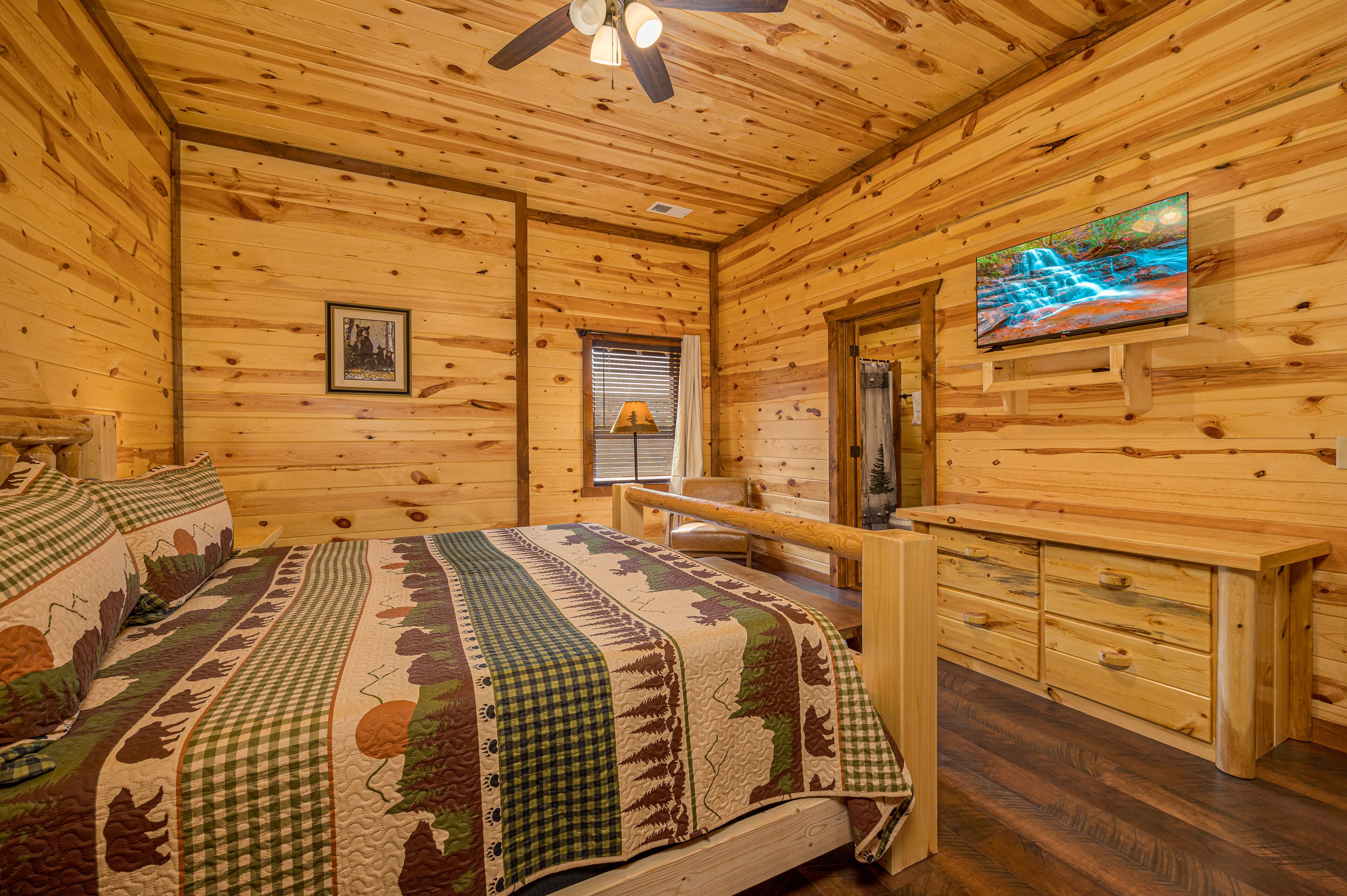 Une chambre dans une cabane en bois, avec un lit, une télévision, un banc et une commode.
