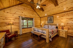 Un dormitorio de cabaña de madera con cama, un banco, un escritorio y una ventana.