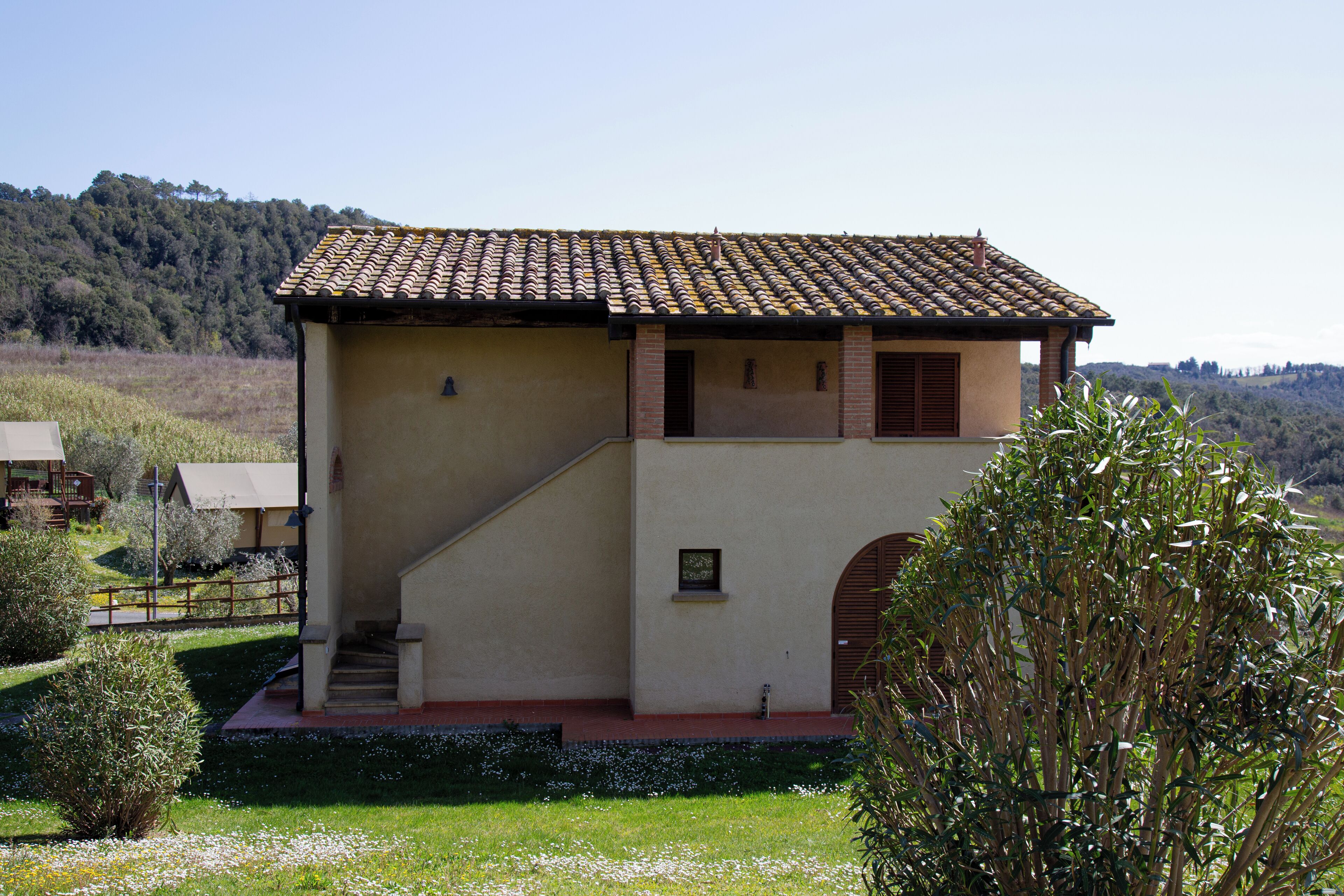 Edifici de dues plantes amb teulada de rajola, escala que condueix a la planta superior i una petita entrada d'arc.