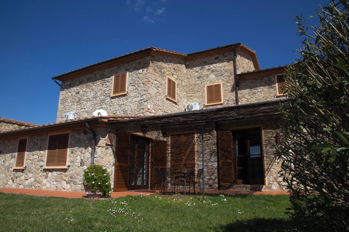 A stone building with multiple windows and a covered porch.
