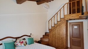 A bedroom with a wooden staircase, a bed with a quilted duvet, and a wooden door. - Resort Le Tegole (Riparbella)