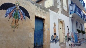 Ein Gebäude mit einer blauen Tür und einem Mosaikbild an der Wand.