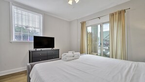 Ein Schlafzimmer mit einem Bett, einem Fernseher auf einer Kommode und einem Fenster mit Jalousien.