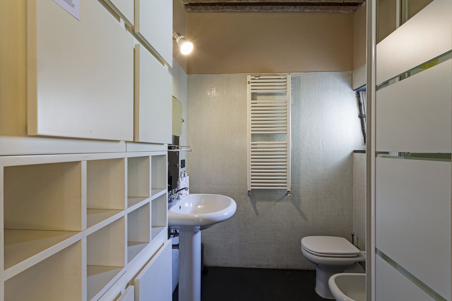 Ein kleines Badezimmer mit einem weißen Waschbecken, einer Toilette und einem Handtuchhalter.
