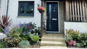 A two-story house with a black front door, two windows on the upper floor, and a grey roof. - Beautiful Cottage close to the beach w/ sunny garden (Crantock)