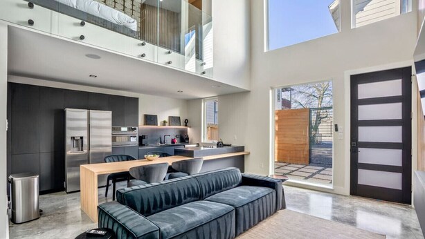 Ein modernes Apartment mit Essbereich, Küche und einem großen Fenster.
