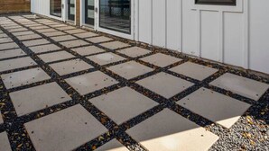 Ein modernes Gebäude mit großen Fenstern, einem überdachten Eingang und einem gepflasterten Weg.