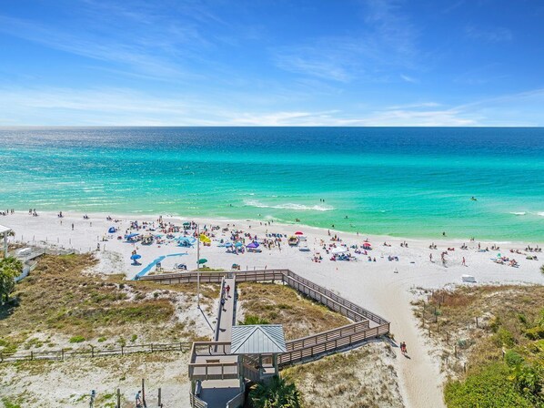 Guests can enjoy a scenic beach view from the resort's walkway, which leads to a beach area with sun loungers and umbrellas.