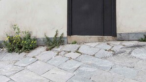Una puerta negra con un arco decorativo de metal encima, un letrero que dice "VIA DEL CELSO" y el número de casa "145".