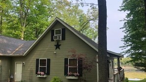 Una casa verde con una stella sulla facciata, un portico e un piccolo giardino.