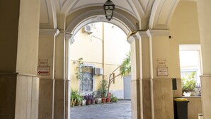 Un corridoio ad arco con piante in vaso e cartelli che indicano le dimensioni delle stanze.