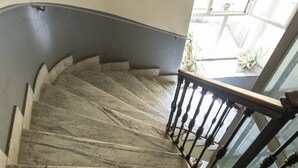 Una scalinata in marmo con ringhiera in legno e balaustra in vetro.