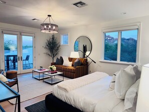 Una habitación de hotel moderna con una cama, un sofá, una mesa de centro, una mesa de comedor y un amplio ventanal con vistas a la montaña.